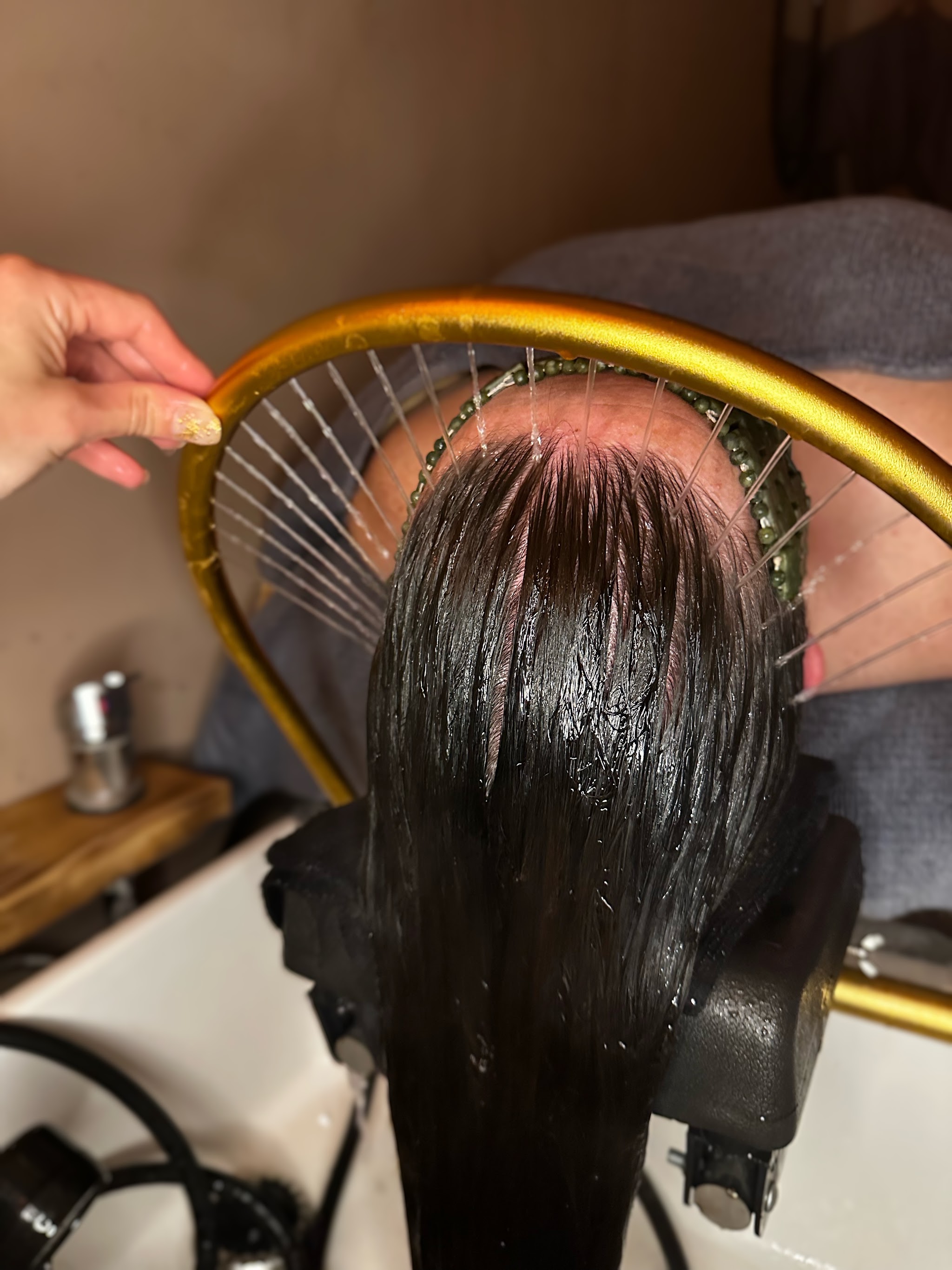 The halo rinse from above, long dark hair over the basin